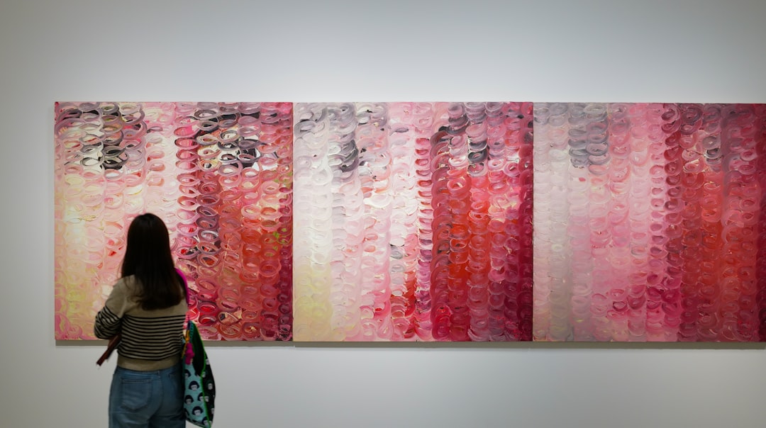 A woman looking at three abstract oil paintings connected together